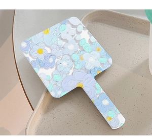 Detail of blue floral hand-held makeup mirror with oil painting texture on beige tray