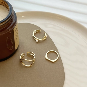 Three-piece gold geometric ring set with pearls and wave designs on a chic plate