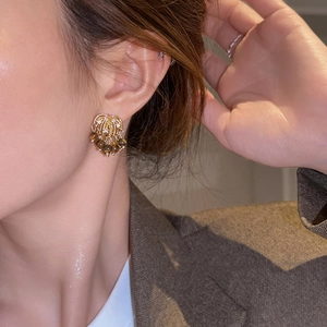 Elegant tiger eye tassel stud earrings with gold accents worn by a model in casual blazer