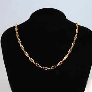 Close-up of golden necklace with colorful rectangular zircon stones on a black bust