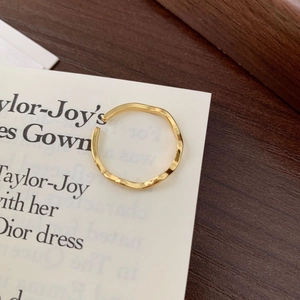 Minimalist 925 sterling silver wavy ring in gold finish on a rustic wooden base