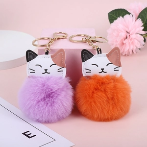 Detail of purple and orange faux fur lucky cat keychains with golden metal hardware