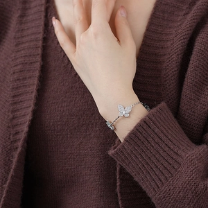Detail of silver butterfly bracelet with clear zircons worn by a woman on wrist