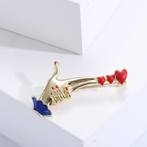 Detailed view of enamel heart gesture pin with gold finish on white background