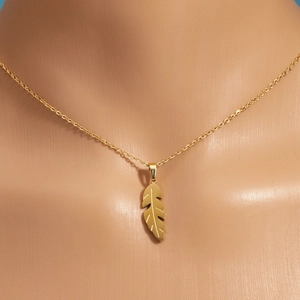 Titanium steel gold feather pendant necklace on mannequin neck for elegant display