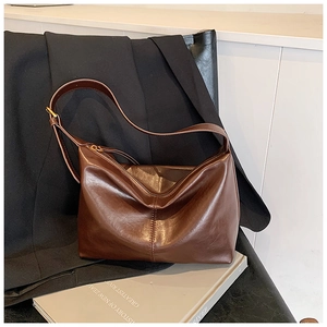 Close-up of a dark brown leather tote bag with vertical stitching and gold zipper detail