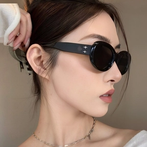 Detail shot of black oval sunglasses featuring silver star metallic decor on temples