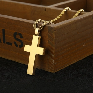 Polished gold cross pendant necklace with rope chain on a vintage wooden box