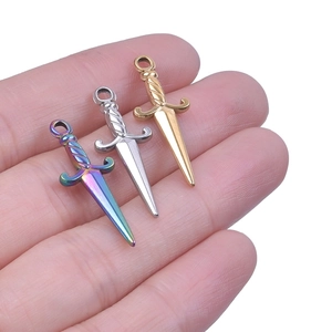 Detailed view of small stainless steel dagger charms in rainbow, gold, and silver finishes