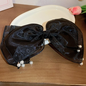 Detail of a large black mesh bow hair clip with elegant pearl tassel decorations