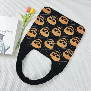 Close-up of black knitted tote bag featuring orange skull jacquard and textured fabric