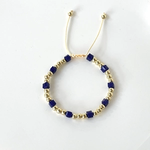 Detailed macro of gold plated beads and blue square crystal bracelet with cord closure