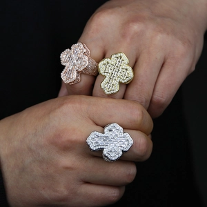 Macro view of wide iced-out cross rings with shiny zircons on a model's hand