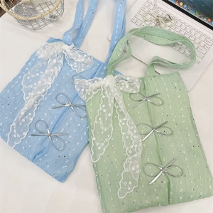 Detail of sequined canvas tote bag with lace trim and silver bow accents in light blue