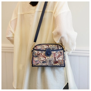 Detail view of canvas crossbody bag with teddy bear print and navy leather trim on model