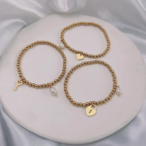 Detailed shot of three gold beaded bracelets with pearl charms and heart-shaped pendants