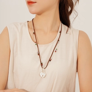 Detail of double-layer necklace with silver heart lock pendant and brown leather cord