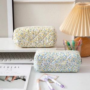 Quilted floral pencil cases with zipper closure on a white desk with aesthetic decor