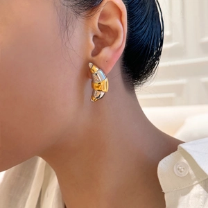 Detail of two-tone gold and silver croissant earrings worn on model profile