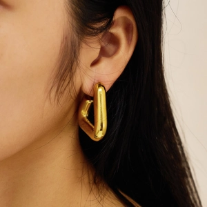 Close-up of a woman wearing gold geometric hollow trapezoid earrings with a polished finish
