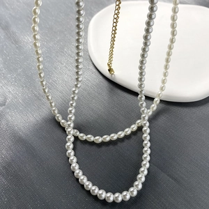 Close-up of pearl necklace with golden metal extension chain on minimalist plaster tray
