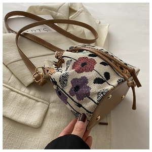 Detail of vintage woven bucket bag with floral embroidery and golden base studs