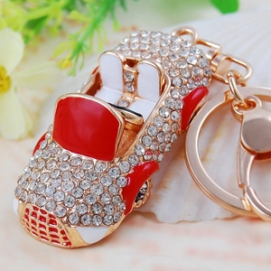 Close-up of a sparkling rhinestone-encrusted metal convertible car keychain in red and gold
