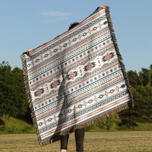 Detail of bohemian woven throw blanket with geometric patterns and fringe edges on grass