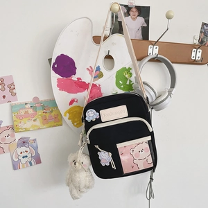 Détail d'un sac bandoulière en toile noire avec imprimé ours et charmant ours en peluche