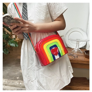 Close-up of rainbow crossbody bag featuring glossy leather finish and heart detail