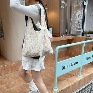 Detail of floral canvas tote bag with delicate white lace bow accent in an outdoor setting