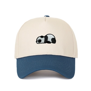 Detailed embroidery of a panda lying on a two-tone beige and navy cotton baseball cap