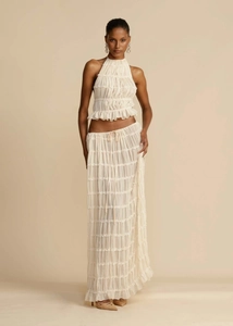 Detailed close-up of cream halter top with elegant horizontal pleats and textured fabric