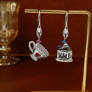 Detail of asymmetric cupcake and teacup earrings with colorful zircons and heart gems