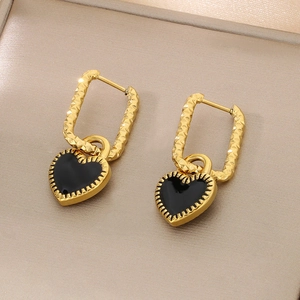 Détail de boucles d'oreilles carrées dorées avec pendentif cœur noir en émail