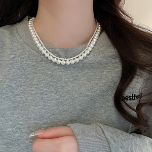 Close-up of double-layer necklace with large white pearls and a small silver bead chain