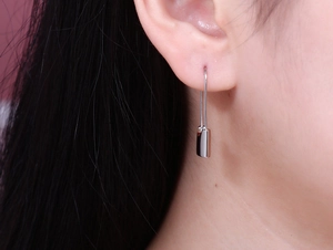 Close-up of minimalist silver safety pin earrings with polished finish on model