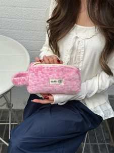 Detailed shot of pink plush makeup bag with faux fur texture and top handle