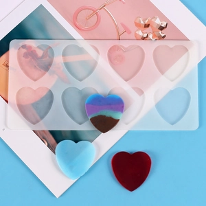 Flat lay of heart silicone mold with multi-colored resin crafts on blue surface