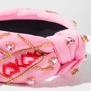 Dettaglio cerchietto rosa in tessuto con ricamo LOVE e cristalli a forma di cuore