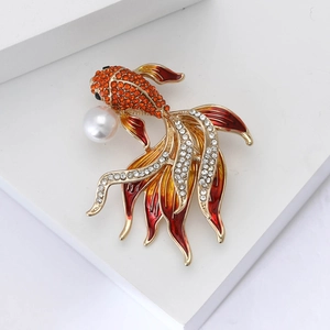 Dettaglio della spilla a pesce con strass arancioni, smalto rosso e perla bianca chic