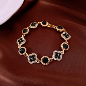 Vue macro d'un bracelet doré avec pierres bleu foncé et cristaux blancs sur soie