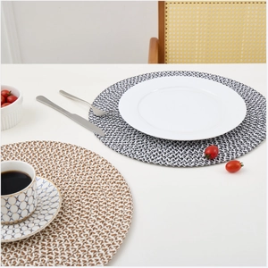 Close-up of woven round placemats in two-tone patterns on a stylishly set dining table