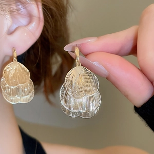 Close-up of golden multi-layer petal earrings with brushed texture on female model