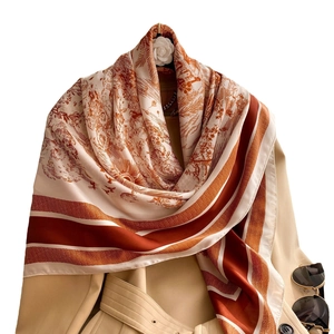 Vintage floral silk scarf in orange and beige draped over a trench coat for elegant style