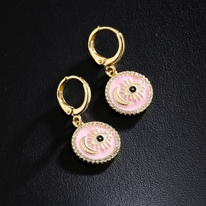 Gold-plated evil eye earrings with pink enamel and sparkling crystals on black background