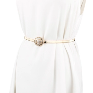 Détail de la ceinture dorée élastique à ressort avec boucle strass sur robe blanche