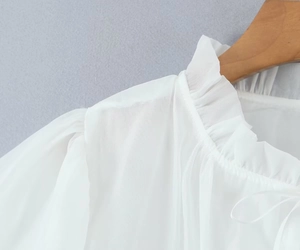 Dettaglio del colletto a balze e maniche a sbuffo su una camicetta bianca in chiffon
