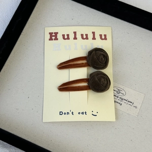 Pair of brown velvet rose hair clips for women displayed on a beige vintage card