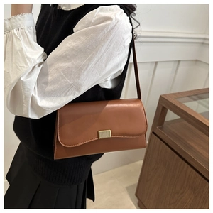 Detail of vintage brown leather shoulder bag with textured gold rectangular buckle clasp